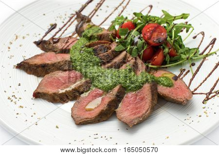 sliced veal steak medium rare with sauce on a white plate white background