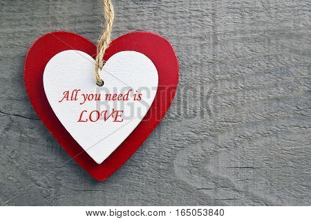 All You Need Is Love.Decorative red and white wooden hearts on a grey wooden background.Two Valentine hearts.Valentine's Day or Love concept.Selective focus.