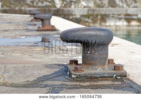Old iron mooring cleat on a concrete pier