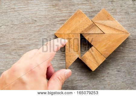 Man held piece of tangram puzzle to fulfill the heart shape on wooden table