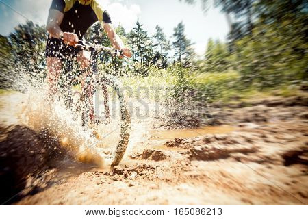 young man riding his mountain bike through a dirty puddle
