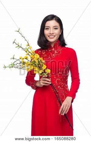 Portrait of a beautiful Asian woman on traditional festival costume Ao Dai holding Hoa Mai tree (Ochna Integerrima) flower. Tet holiday. Lunar New Year.