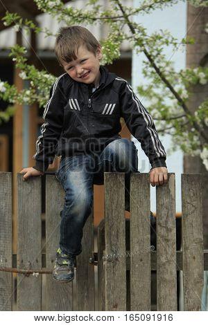 STINKA UKRAINE - APRIL 14 2016 - little country kid sits on a fence at the yard on April 14 2016 in Stinka village