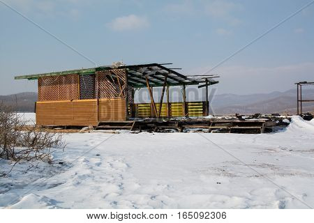 Semi destroyed wooden gazebo. Summer pavilion in winter day.