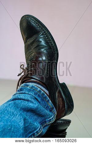 Close up men wear blue jean and brown leather shoes on floor.