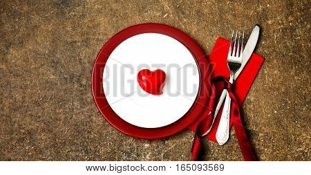 Festive table setting for Valentines Day or Wedding with a fork, knife and hearts on a dark wooden table. The view from the top.