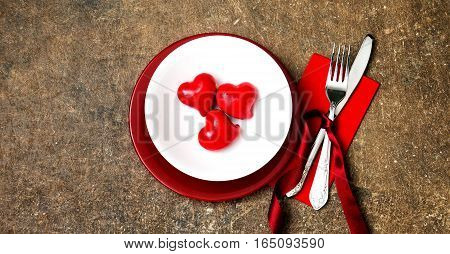 Festive table setting for Valentines Day or Wedding with a fork, knife and hearts on a dark wooden table. The view from the top.