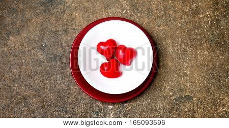 Festive table setting for Valentines Day or Wedding with a fork, knife and hearts on a dark wooden table. The view from the top.