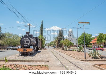 FAURESMITH SOUTH AFRICA - DECEMBER 31 2016: A steam locomotive and the town hall in Fauresmith one of only three towns on earth where the railway line runs down the centre of the main road