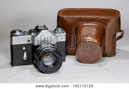 Gatchina, Russia - January 14, 2017: The old Soviet film camera Zenit. Photographed on a bright background. To the right of the camera is its leather case.
