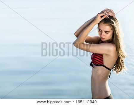 Young sexy woman in swimsuit in fron of the sea background