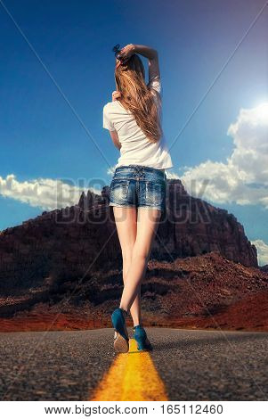 attractive girl walking along the road in the desert under the scorching sun