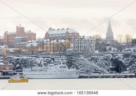 STOCKHOLM - JAN 08 2017: Passenger ferry in the harbor Stadsgarden and old buildings in central Stockholm a cold winter morning ice on the sea. January 08 2017 in Stockholm Sweden