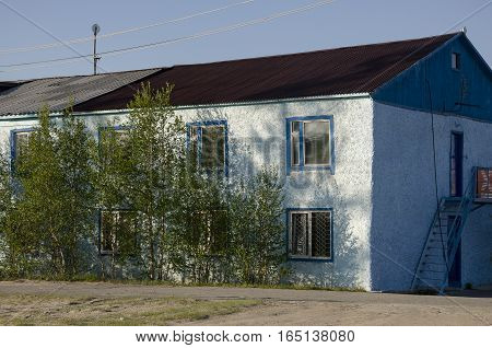 Blue misery and poor two-storeyed building with trees around