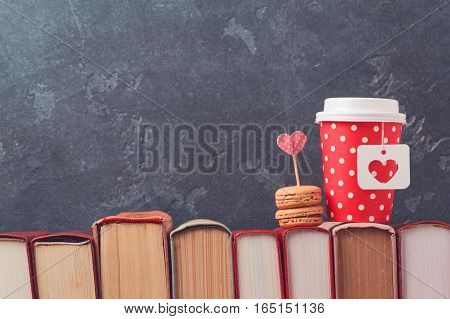 Valentines day concept with paper coffee cup macarons and vintage books over blackboard background