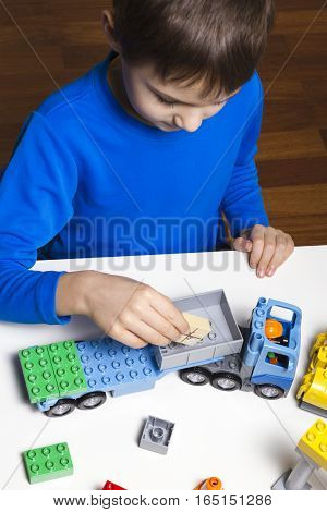 Little kid boy playing with colorful plastic blocks indoor. Top view