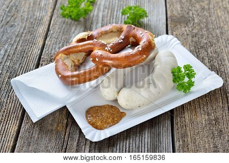 Bavarian street food:  Two Munich white sausages with a fresh pretzel and sweet mustard on a paper plate