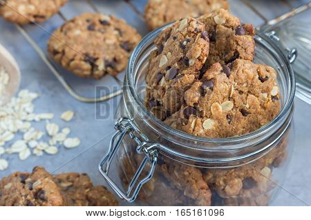 Flourless gluten free peanut butter oatmeal and chocolate chips cookies in glass jar and on table horizontal