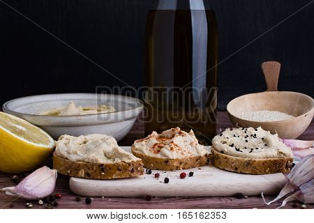 Sandwiches with hummus and few ingredients in rustic light.