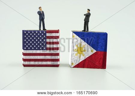 abstract 2 mini businessman stand on block of USA and Philippines flag on isolate background