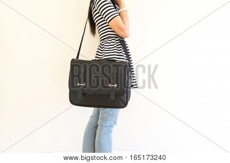Women stand black carrying leather shoulder bag.