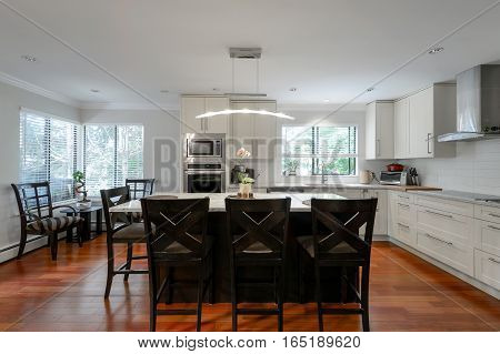 Modern kitchen and dining room interior with stainless steel appliances in a luxury house.