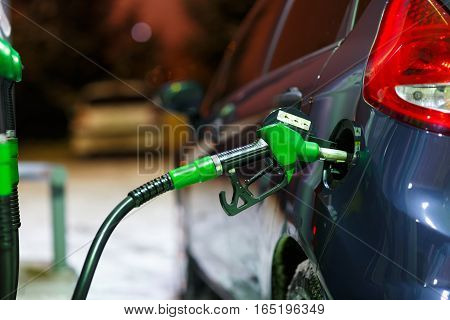 Car refueling on a petrol station in winter at night closeup