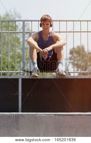 Tired Skater Sitting On A Ramp In Headphones