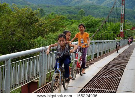 Vietnamese Children Ride Bicycle On Suspension Bridge