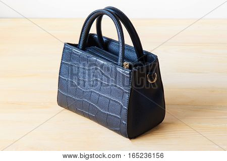 Black female leather bag on wooden background flat lay.