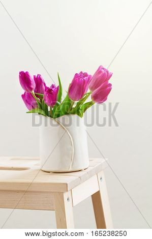 Beautiful Fresh Spring lila Tulips in Vase on Wooden Stool. Spring easter or Mother's Day Concept.