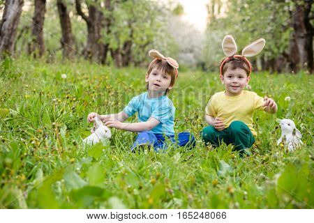 Two Little Kids Boys And Friends In Easter Bunny Ears During Traditional Egg Hunt In Spring Garden,