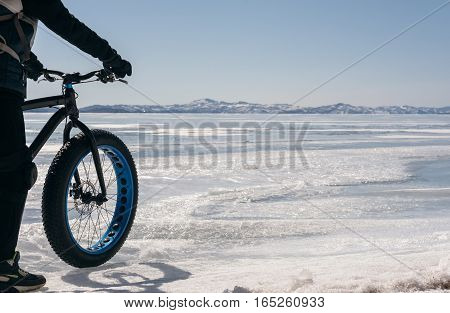 Fatbike also called fat bike or fat-tire bike - Cycling on large tire wheels. Cyclist goes to his bike on the frozen lake.