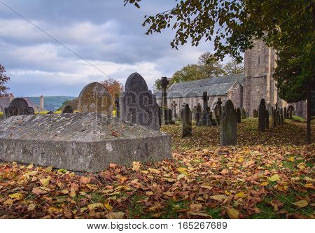 Graveyard near the church. Autumn. Fallen dry leaves lying on the ground. The clouds in the sky. Chagford. Dartmoor. Devon. UK