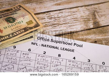Office Superbowl Pool grid with money on a wooden table