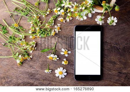 vintage style black smart phone and white flowers on an old wooden board background hipster lifestyle with copy space