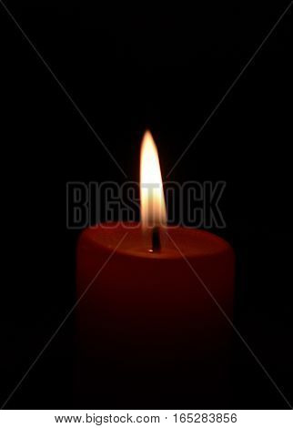 single burning red candle close up on black background with copyspace