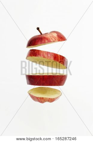 Fresh red golden delicious apple cut into slices floating isolated on white background.