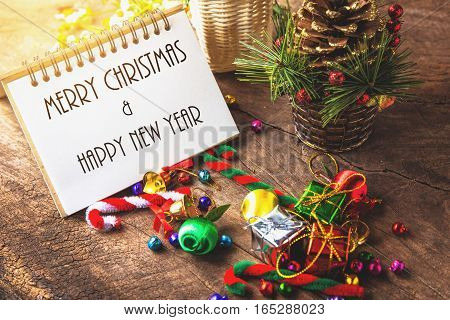 Merry christmas and Happynew year text on blank notebook with gift box daisy flower candy ball and cane pine decoration on vintage wooden background.