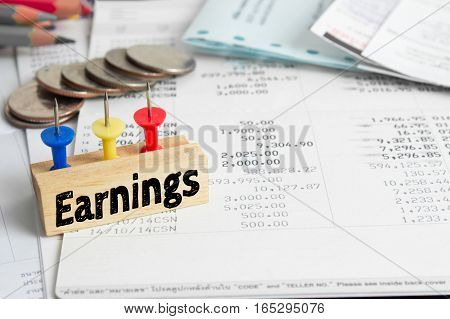 Text message Earnings on wooden with book back, Finance concept