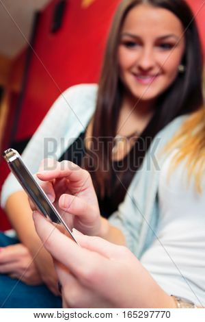 friends having fun at a cafe, texting on their smart phone