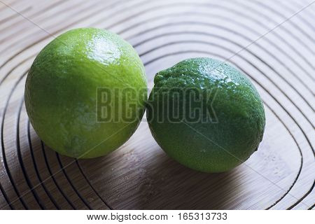 fresh green lemon on wooden background, closeup