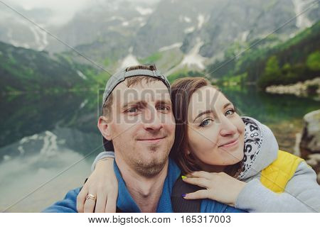 Happpy couple taking selfie withe lake background in the mountains