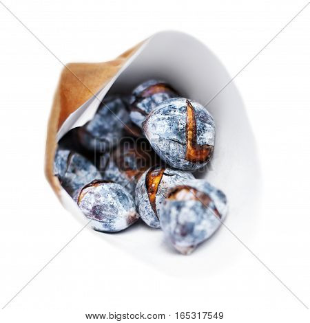 Roasted chestnuts in a craft paper bag isolated on white background close up. Heap of grilled edible chestnut