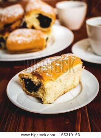 Baked sweet buns with poppy and coffee on wood table