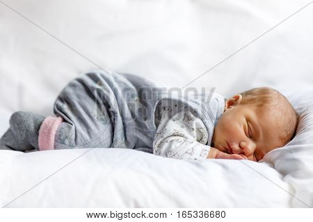 Cute adorable newborn baby sleeping in white bed. New born child, little girl six days old laying in bed. Family, new life, childhood, beginning concept.
