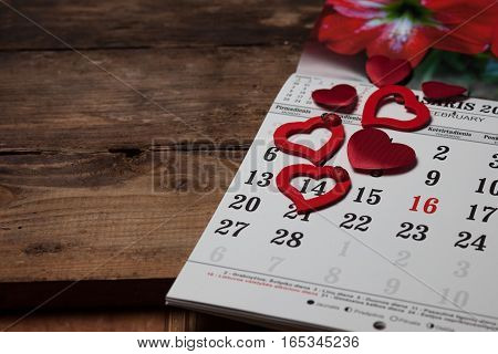 A calendar with hearts on the wooden table