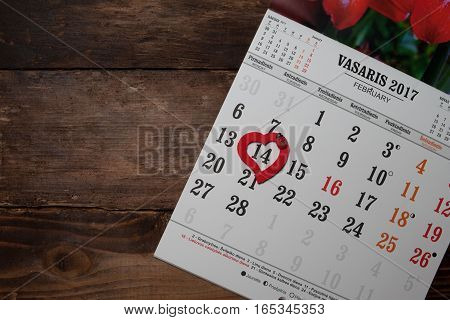 A calendar with hearts on the wooden table
