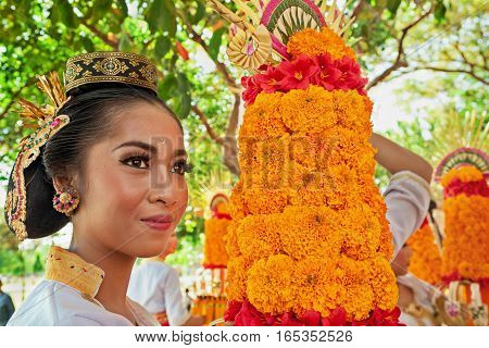 DENPASAR BALI ISLAND INDONESIA - JUNE 11 2016: Beautiful woman in traditional costume. Group of Balinese people with religious offering for hindu ceremony on parade at art and culture festival.