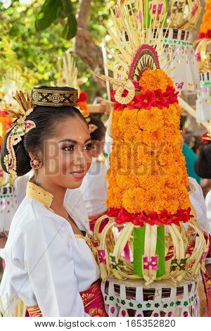 DENPASAR BALI ISLAND INDONESIA - JUNE 11 2016: Beautiful woman in traditional costume. Group of Balinese people with religious offering for hindu ceremony on parade at art and culture festival.